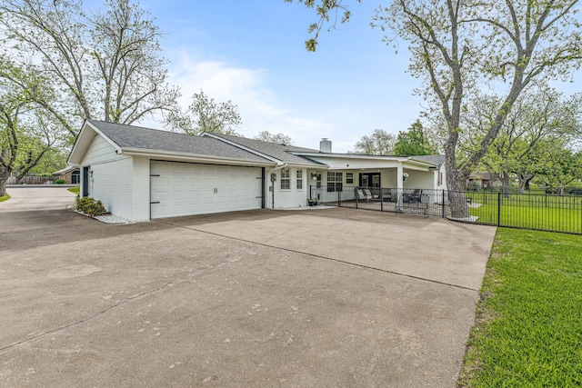 view of front of home with concrete driveway, a front lawn, brick siding, a garage, and fence