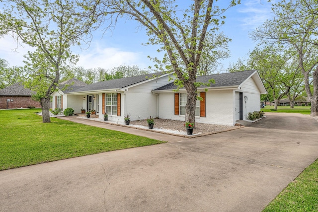single story home featuring brick siding, a front lawn, driveway, and roof with shingles