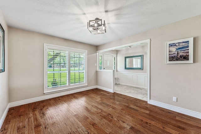unfurnished dining area with baseboards, a notable chandelier, and wood finished floors