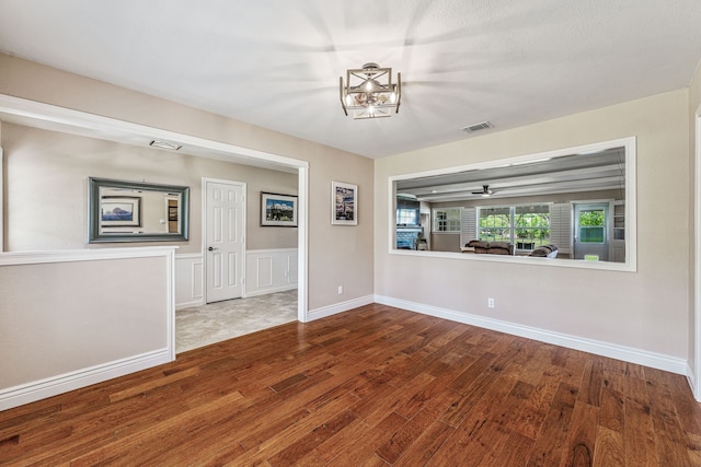 unfurnished living room with visible vents, a notable chandelier, and wood finished floors