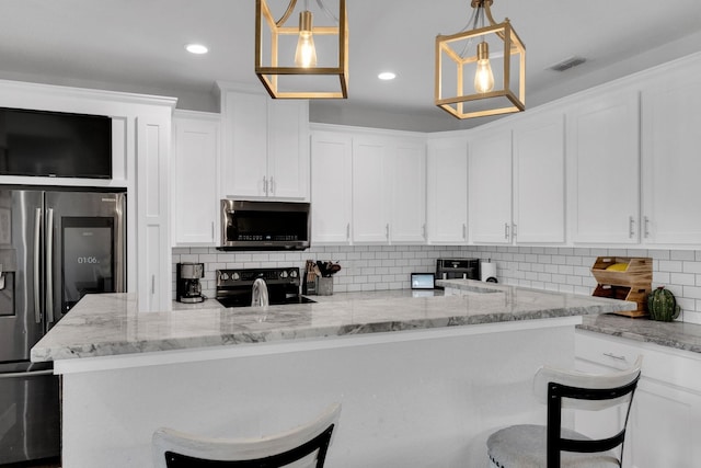 kitchen with white cabinetry, backsplash, visible vents, a kitchen bar, and appliances with stainless steel finishes