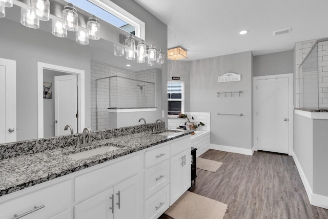 bathroom featuring wood finished floors, a sink, visible vents, and walk in shower