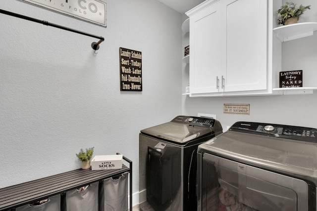 washroom featuring cabinet space and washer and clothes dryer