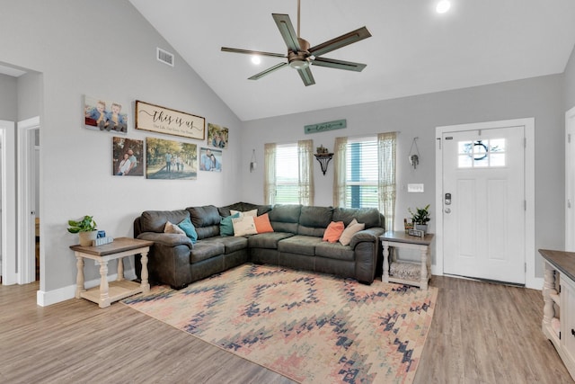 living area with light wood-style flooring, high vaulted ceiling, ceiling fan, and visible vents
