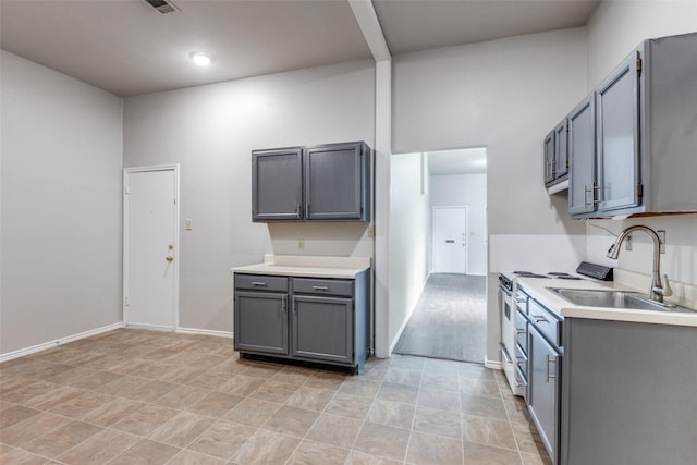 1303 N Church St, Mckinney, TX 75069 - kitchen with white gas stove, gray cabinetry, light countertops, and a sink