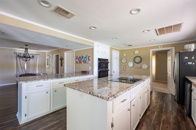 kitchen with a center island, visible vents, ornamental molding, and black appliances