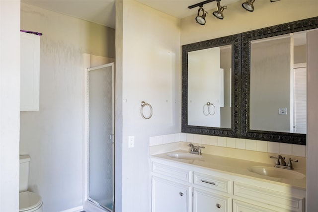 full bath featuring a shower stall, double vanity, a sink, and toilet