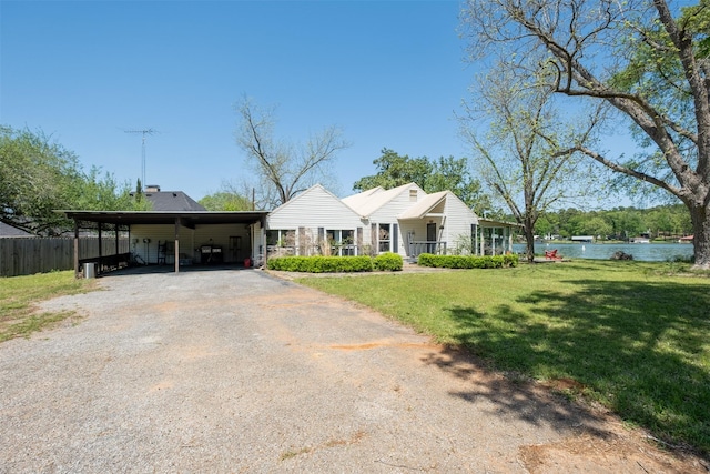 view of front of home featuring a front yard, fence, a water view, and aphalt driveway