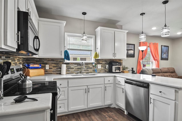 kitchen with a peninsula, white cabinets, light countertops, a sink, and stainless steel appliances