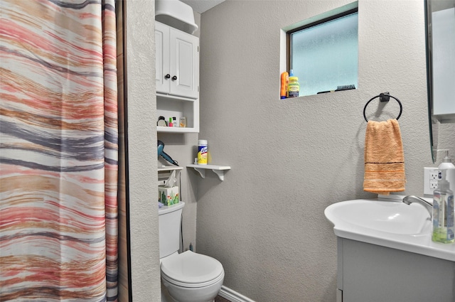bathroom featuring toilet, vanity, and a textured wall