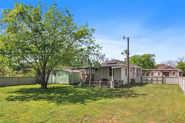 view of yard with a storage shed, a fenced backyard, and an outbuilding