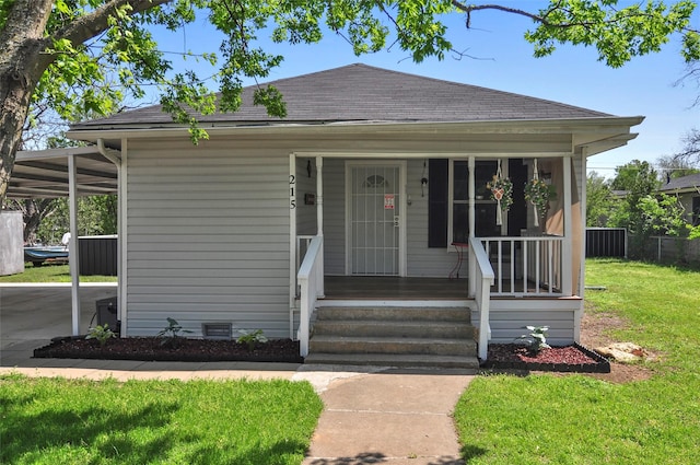 bungalow featuring an attached carport, a front yard, a porch, and a shingled roof
