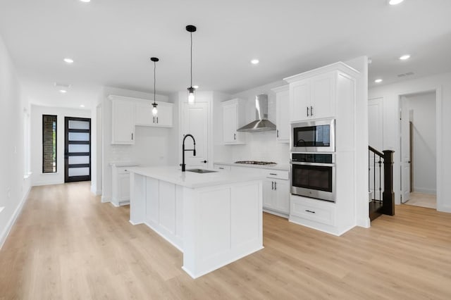 1525 Ginger Ln, Argyle, TX 76226 - kitchen with a sink, stainless steel appliances, wall chimney exhaust hood, light wood-style flooring, and white cabinetry