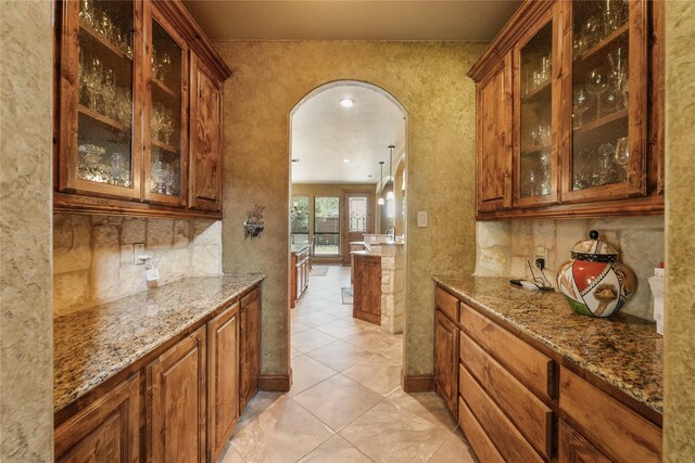 kitchen featuring a sink, appliances with stainless steel finishes, a kitchen island with sink, brown cabinetry, and backsplash