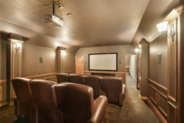 cinema room with dark colored carpet, a textured ceiling, and lofted ceiling