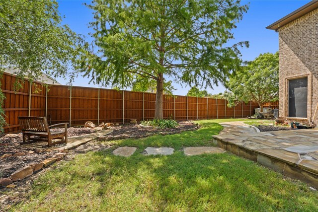 rear view of house featuring a chimney, ceiling fan, a lawn, brick siding, and a fenced backyard