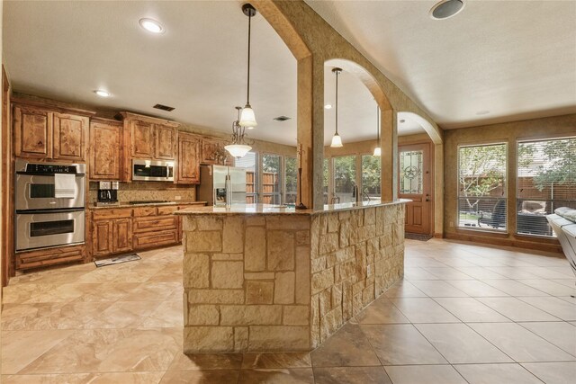 kitchen with arched walkways, tasteful backsplash, stainless steel appliances, and plenty of natural light