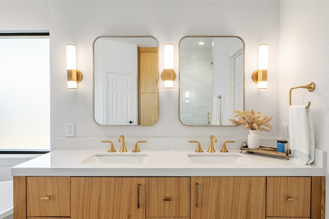 bathroom featuring a shower, double vanity, and a sink