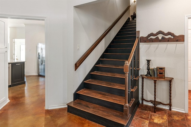 stairway with finished concrete floors and baseboards