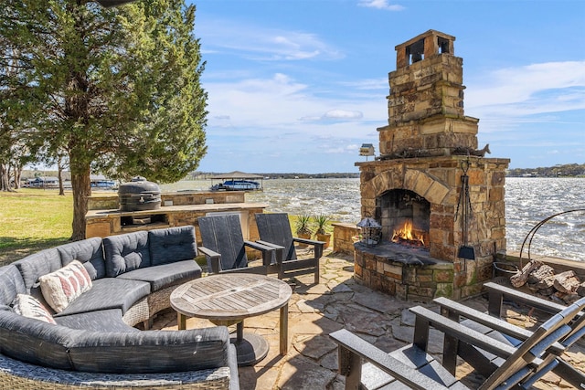 view of patio with a grill, exterior kitchen, an outdoor living space with a fireplace, and a water view
