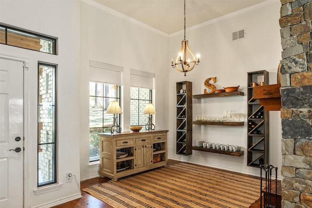 foyer entrance with ornamental molding, visible vents, wood finished floors, baseboards, and a notable chandelier