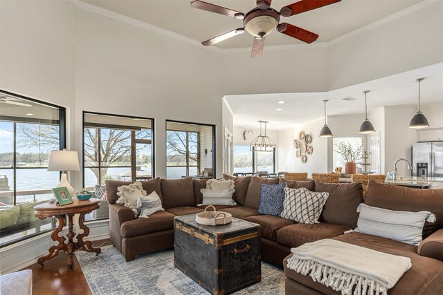 living room featuring a water view, ceiling fan, a high ceiling, and wood finished floors