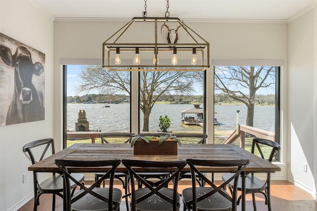 dining area featuring a water view, ornamental molding, and baseboards
