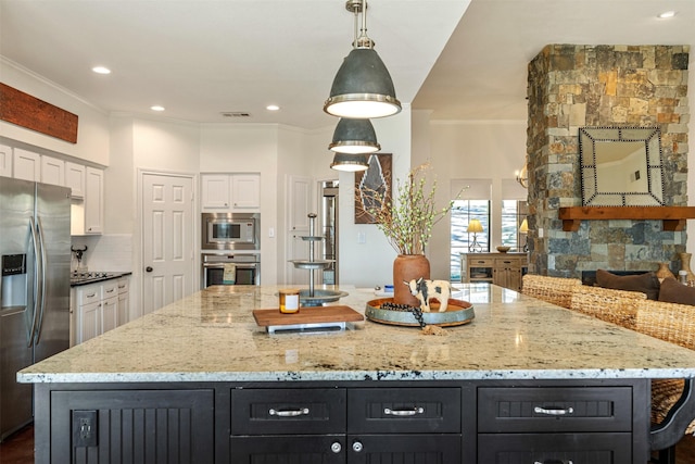 kitchen featuring dark cabinetry, appliances with stainless steel finishes, light stone counters, and white cabinetry