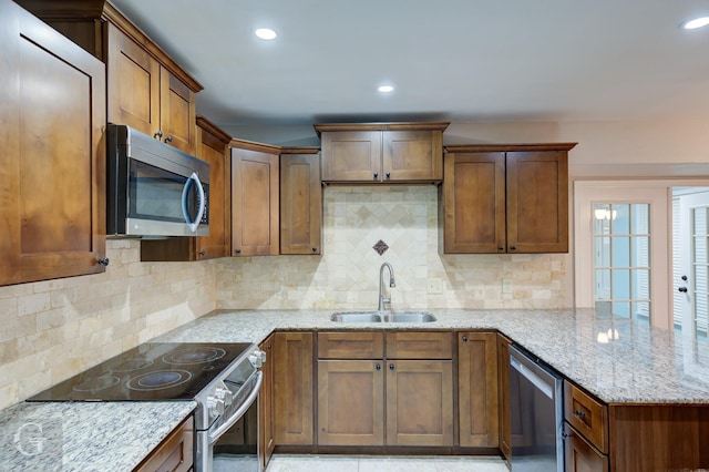 5411 Sage Dr, Bossier City, LA 71112 - kitchen with light stone counters, a peninsula, backsplash, appliances with stainless steel finishes, and a sink