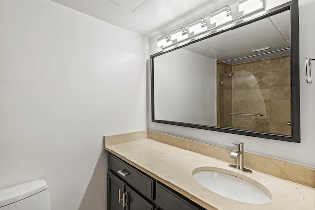 full bathroom with toilet, tiled shower, and vanity