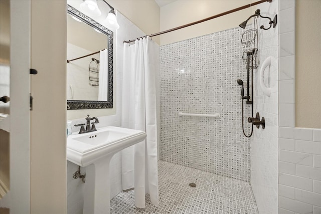 bathroom featuring a tile shower, a sink, and tile patterned flooring