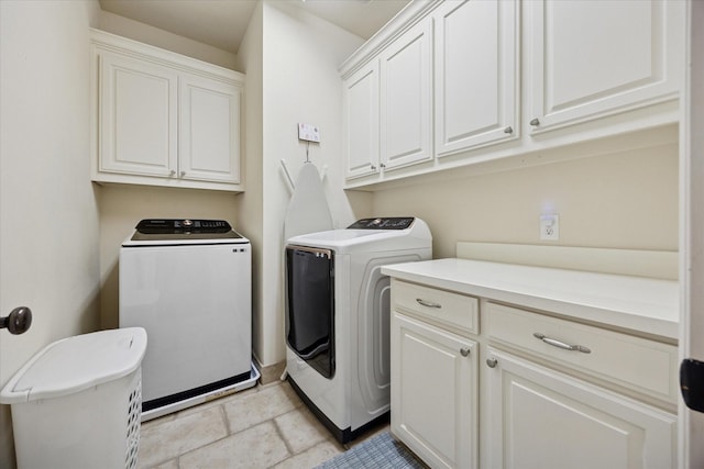laundry room featuring cabinet space, independent washer and dryer, and stone finish flooring