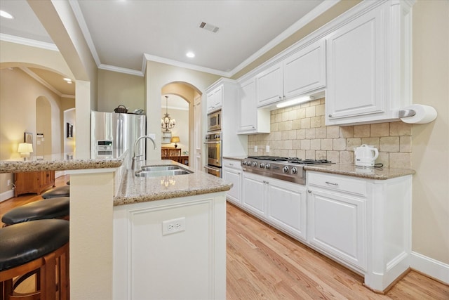 kitchen with visible vents, arched walkways, a sink, appliances with stainless steel finishes, and light wood finished floors