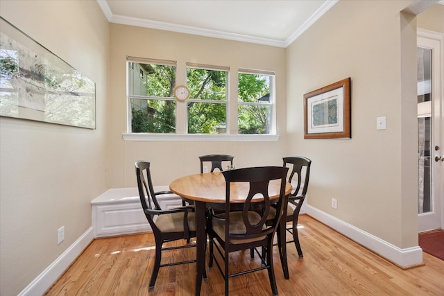 dining area with baseboards, light wood-type flooring, and ornamental molding