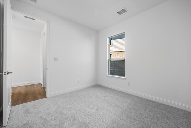 carpeted empty room featuring visible vents and baseboards
