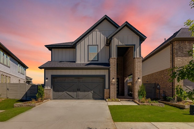 view of front of property with board and batten siding, concrete driveway, a yard, brick siding, and a garage