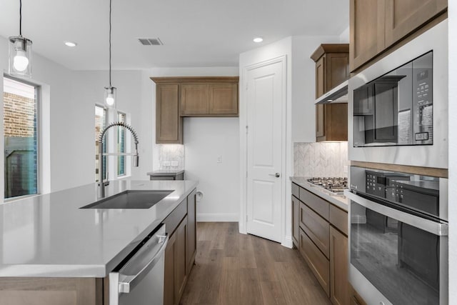 kitchen featuring dark wood finished floors, decorative backsplash, appliances with stainless steel finishes, a sink, and visible vents