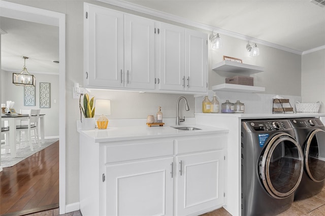 washroom with baseboards, ornamental molding, washing machine and dryer, a sink, and wood finished floors