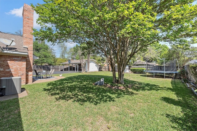 view of yard featuring a trampoline, a fenced backyard, cooling unit, a patio, and an outbuilding