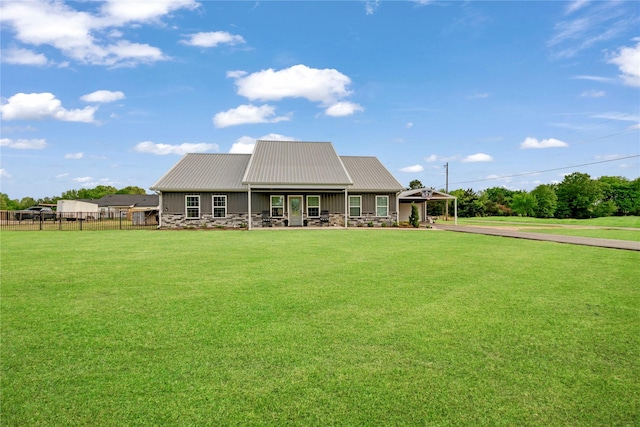 rear view of house with a carport, stone siding, metal roof, a lawn, and driveway