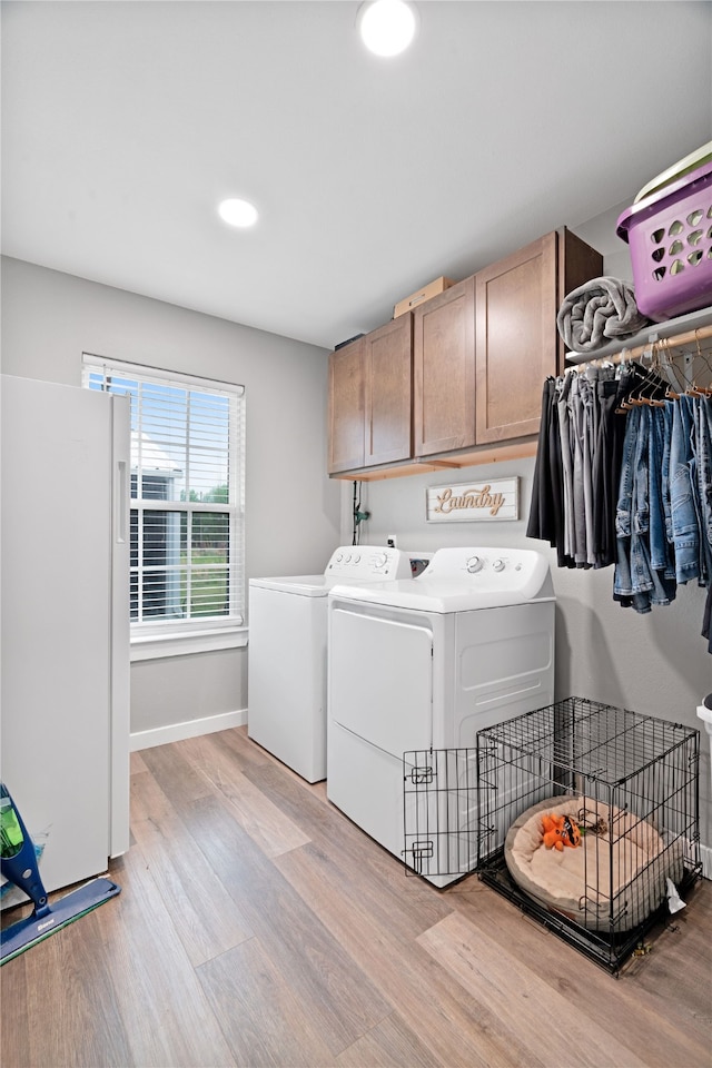 clothes washing area with light wood finished floors, baseboards, cabinet space, and washer and clothes dryer