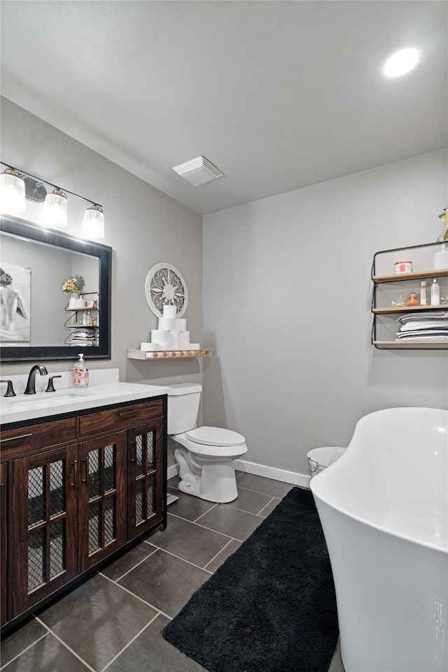 bathroom featuring a freestanding tub, vanity, tile patterned flooring, visible vents, and toilet