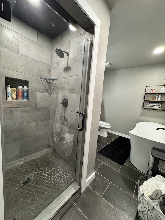 bathroom with tile patterned flooring, toilet, a stall shower, and baseboards
