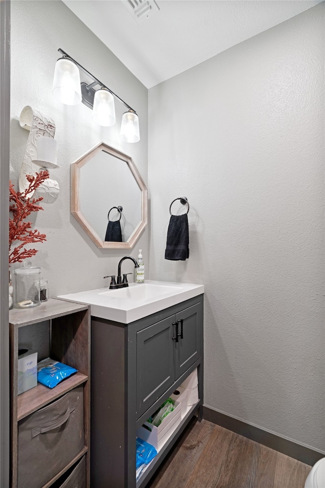 bathroom featuring visible vents, baseboards, vanity, and wood finished floors