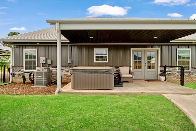 back of property with central AC unit, board and batten siding, fence, and a hot tub