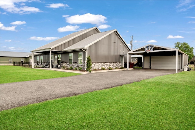 view of front of house featuring a front yard, a detached garage, stone siding, and metal roof
