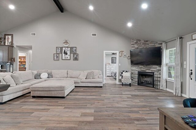living room with high vaulted ceiling, a fireplace, visible vents, and beam ceiling