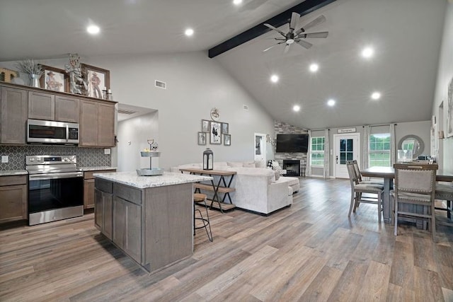 kitchen with high vaulted ceiling, a ceiling fan, visible vents, stainless steel appliances, and open floor plan