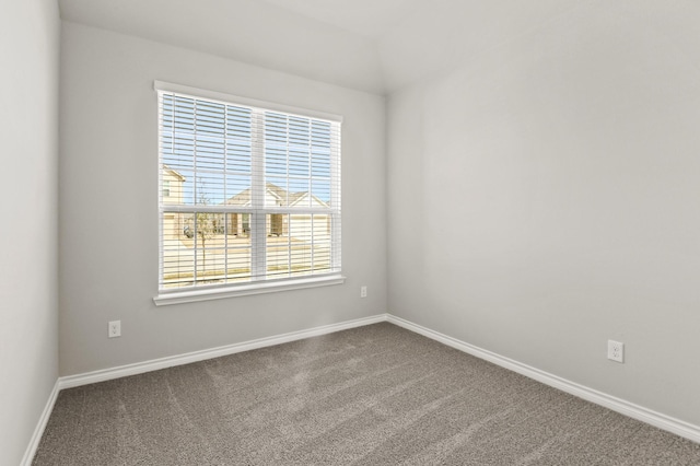 spare room featuring dark colored carpet and baseboards