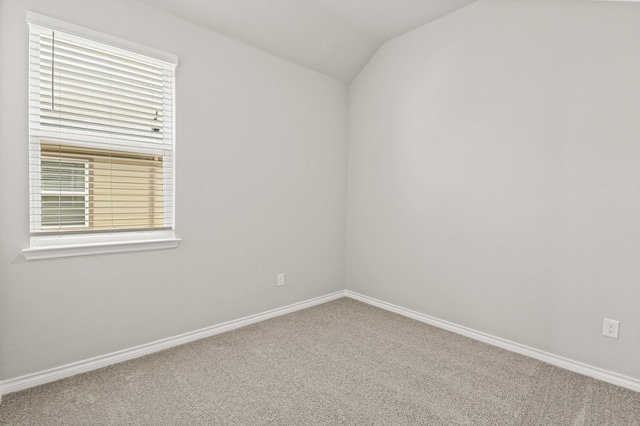 unfurnished room with carpet floors, baseboards, and vaulted ceiling